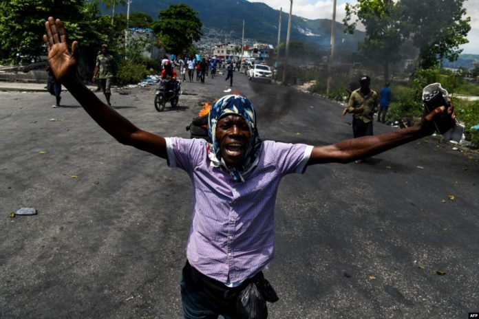 2019-06-13-Haitian-protestor-in-road-AFP-696x464.jpg