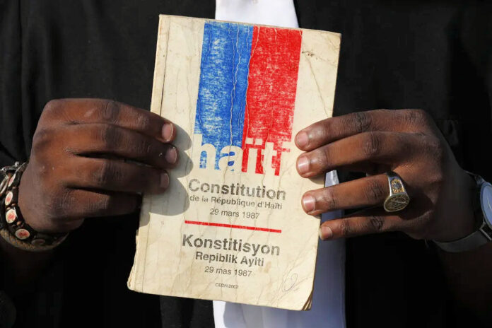 Hand holding Haitian Constitution from Haitian Times